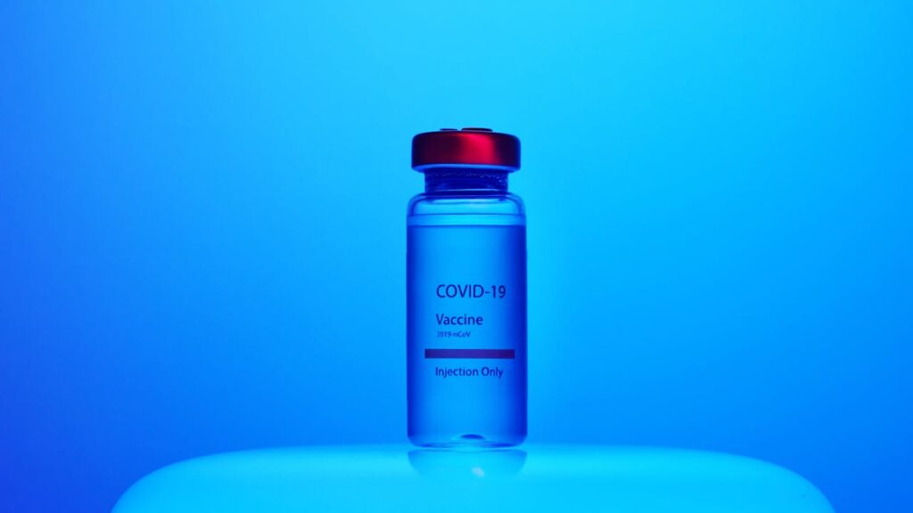 A Close-Up View of a Covid-19 Vaccine Vial on Blue Background